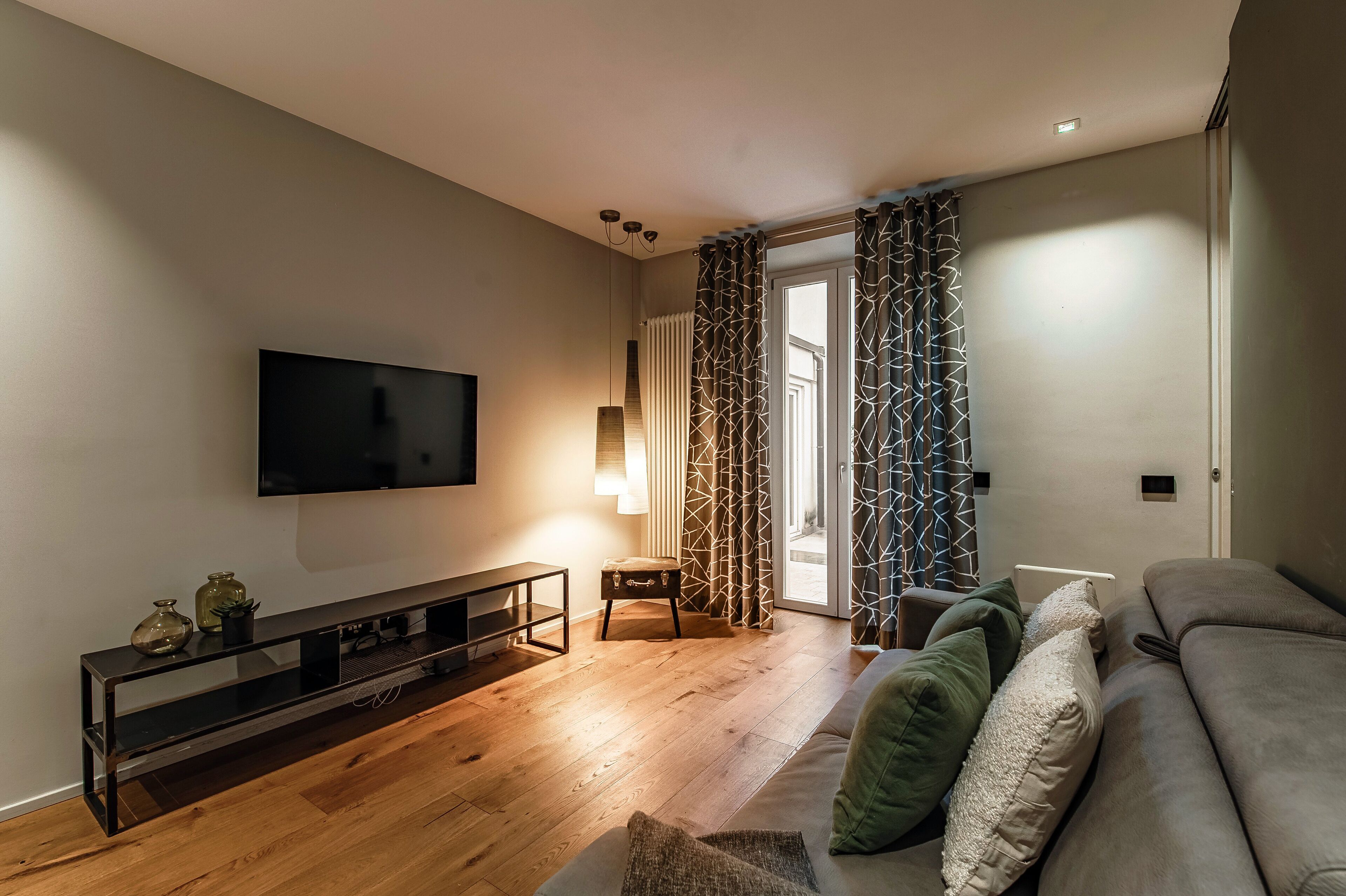 Una sala moderna con televisor de pantalla plana, piso de madera, un sofá y una mesita auxiliar.