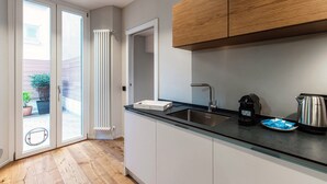 A modern kitchen with a glass countertop, stainless steel sink, and wooden cabinets. - Hidden Lodge (Como)