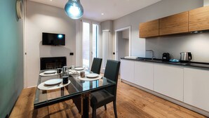 A modern kitchen with white cabinets, a black countertop, and a hanging light fixture. - Hidden Lodge (Como)