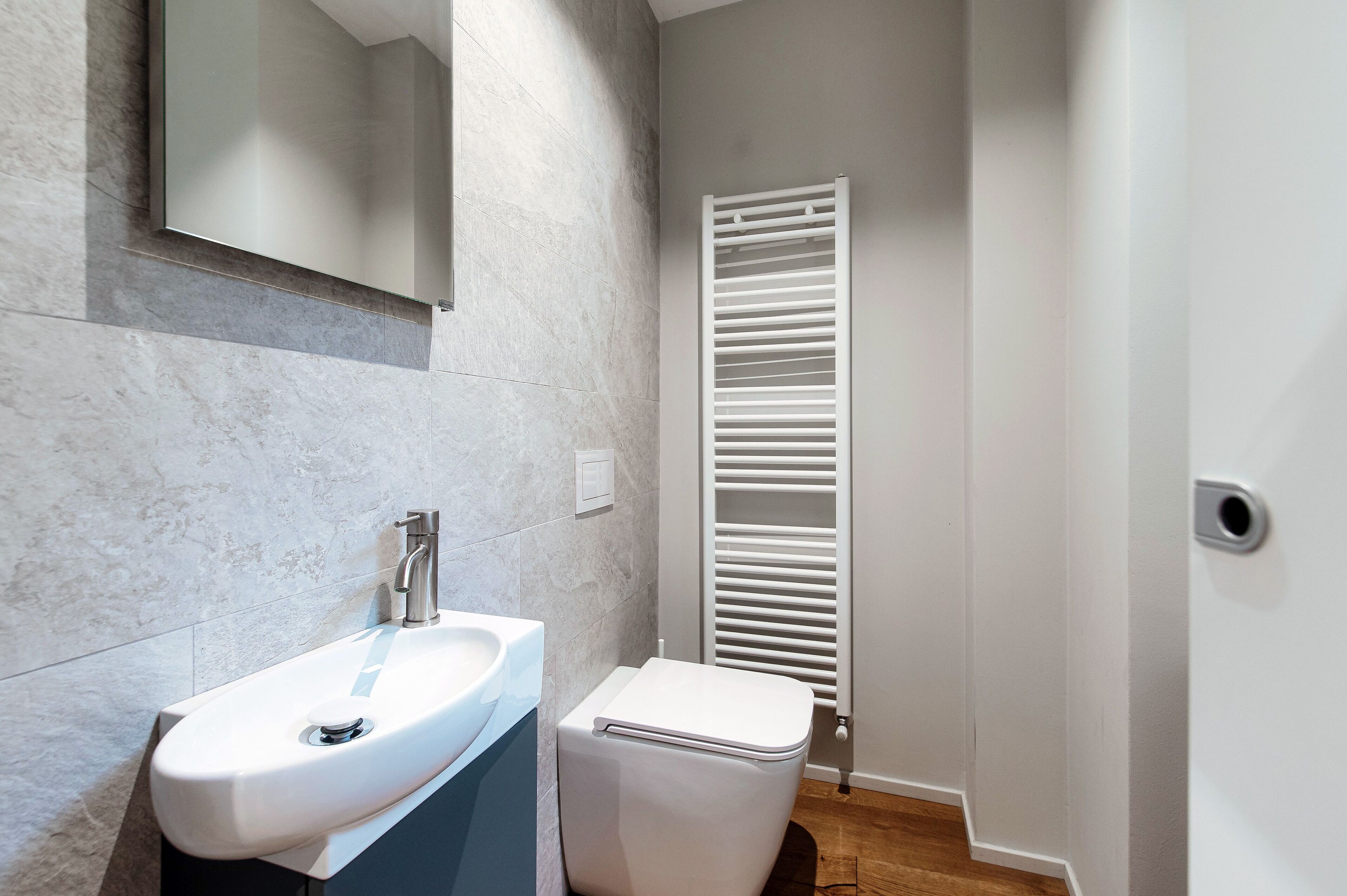 A modern bathroom with a white sink, a toilet, and a white radiator.