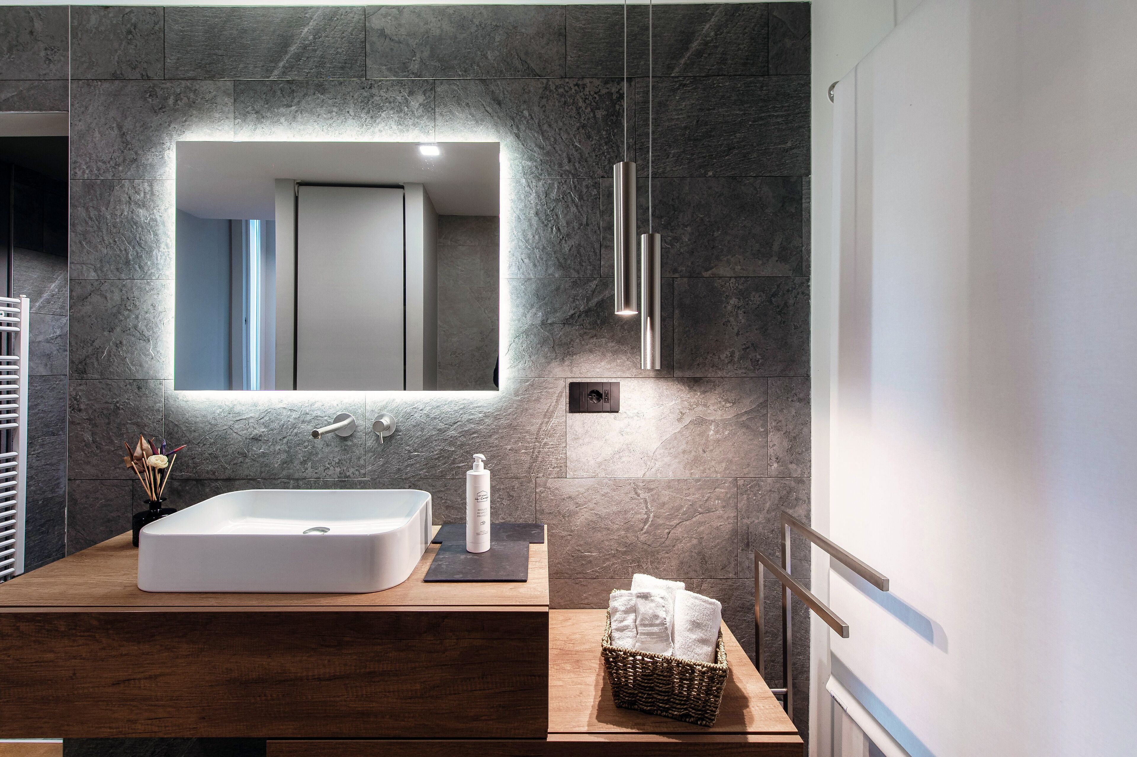 A modern bathroom with a large rectangular sink, a mirror, and a wooden vanity.