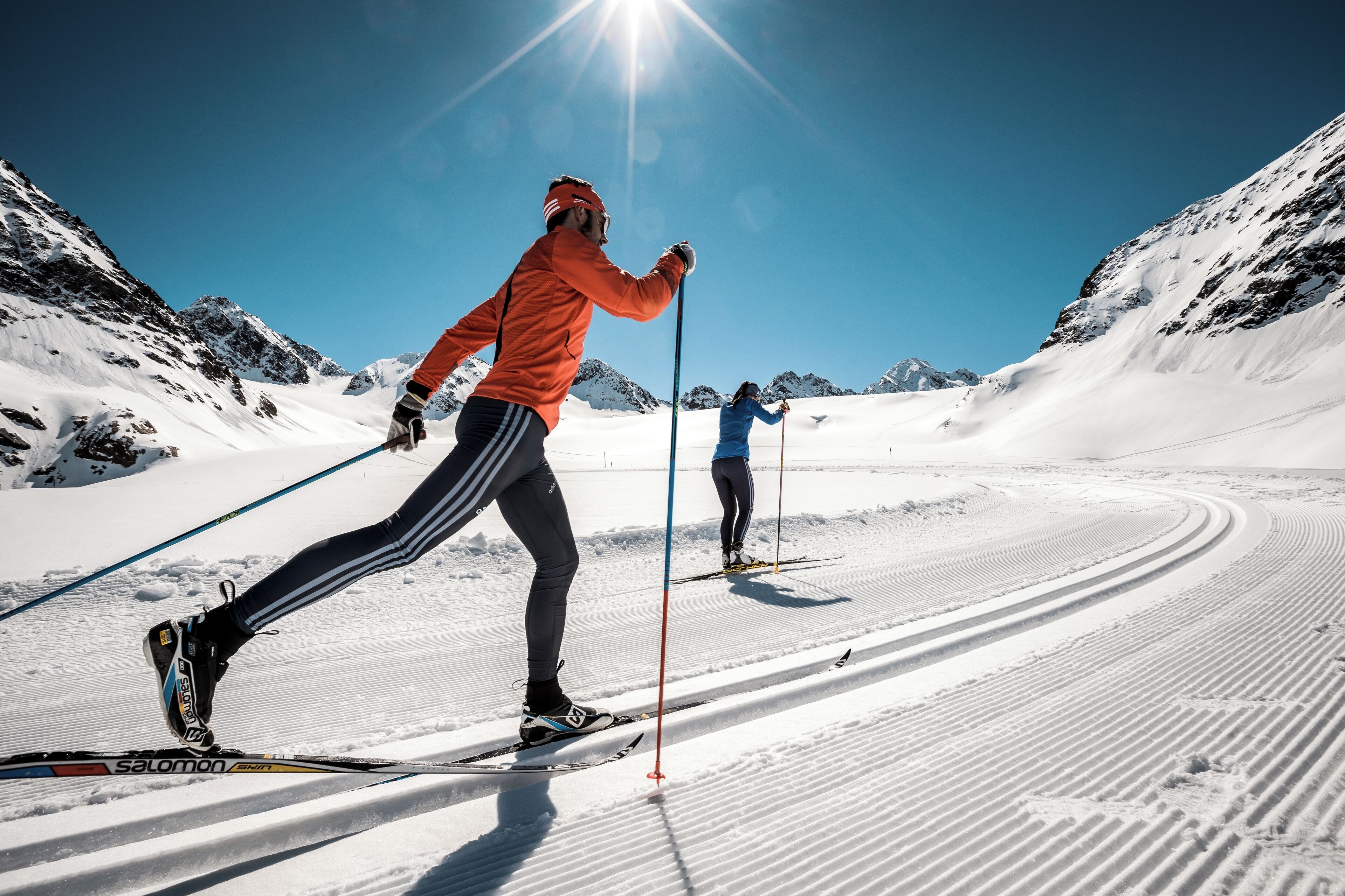Deux skieurs sur une piste enneigée, sous un ciel dégagé.