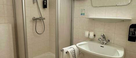 A modern bathroom with a glass-enclosed shower, a white sink, and a mirror above it.