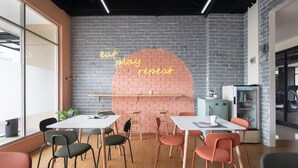 Een moderne vergaderruimte met een bakstenen muur, neonreclame en een koelkast.