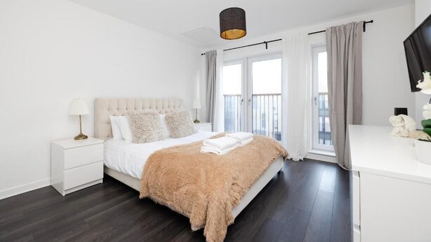 Ein modernes Schlafzimmer mit einem großen Bett, einem Nachttisch, einer Kommode und einem Fenster mit Vorhängen.