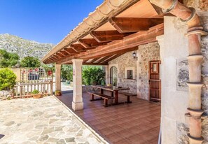 Relax under the pergola, surrounded by a serene stone wall and a wooden fence.