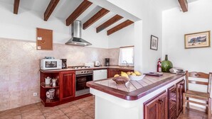 A kitchen with a central island, wooden cabinets, a stove, and a microwave. - Villa Oliveres, Beautiful villa in the countryside near Pollensa (Pollença)