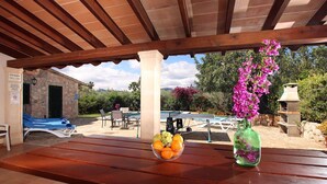 An outdoor patio with a wooden table, a bowl of fruit, and a vase of flowers. - Villa Oliveres, Beautiful villa in the countryside near Pollensa (Pollença)