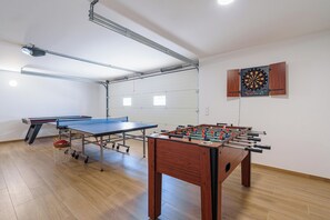 Um quarto com mesa de pingue-pongue, mesa de futebol de mesa e dardos.