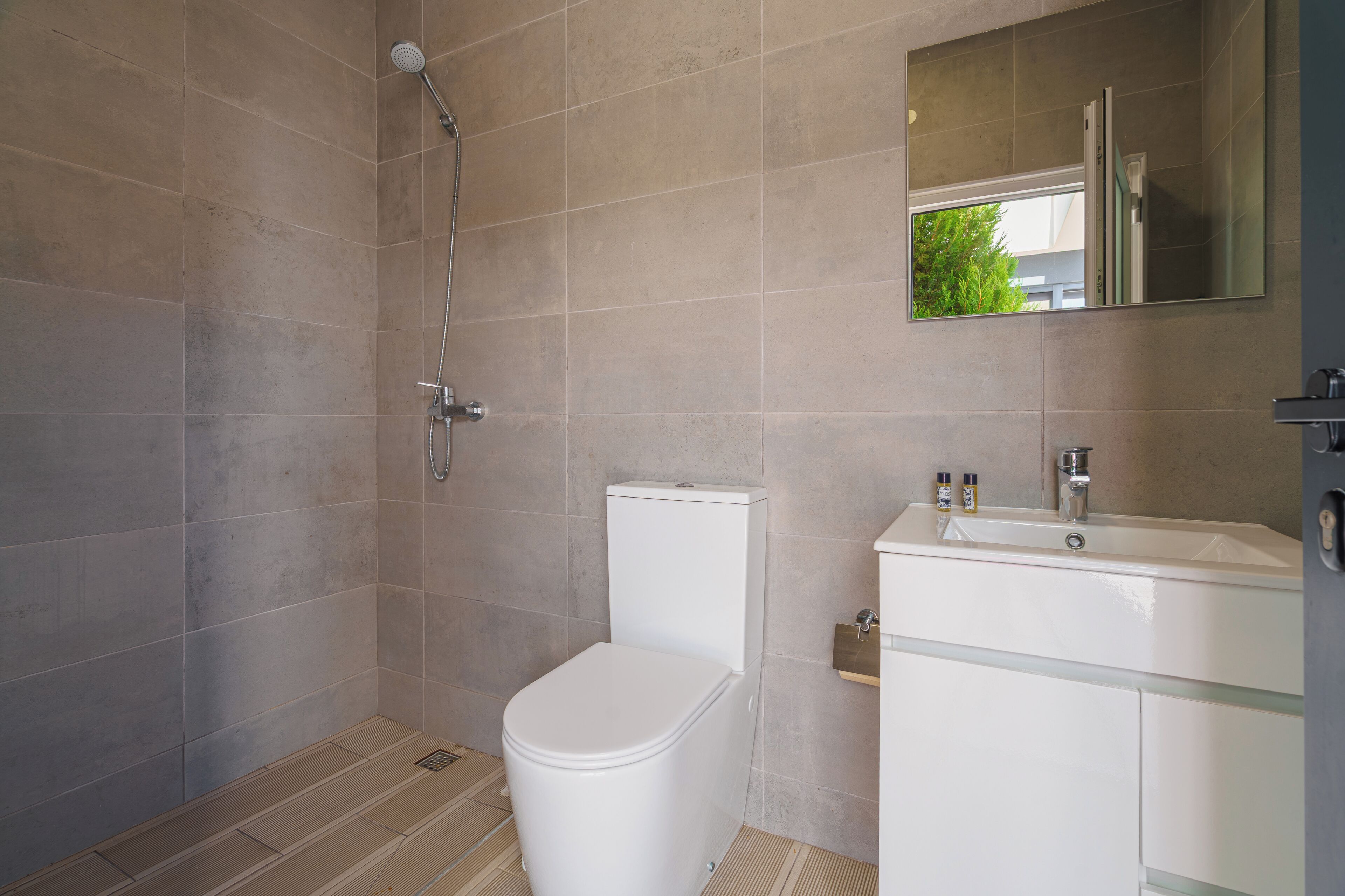 Een badkamer met douche, toilet, wastafel en spiegel.