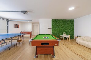 Uma mesa de bilhar, mesa de futebol de mesa e uma parede verde.