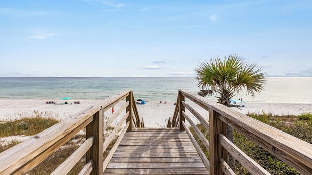 A wooden boardwalk leading to a beach with a palm tree and a clear view of the ocean. - Gulf Views - Private Beach Access Across Street (Seacrest)