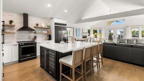 A modern kitchen with a central island, built-in appliances, and a dining area with a sofa and chairs. - Gulf Views - Private Beach Access Across Street (Seacrest)