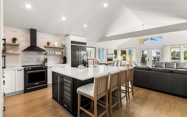 A modern kitchen with a central island, built-in appliances, and a dining area with a sofa and chairs.