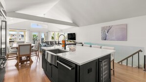 A modern kitchen with a large island, built-in appliances, and a dining area with a view. - Gulf Views - Private Beach Access Across Street (Seacrest)