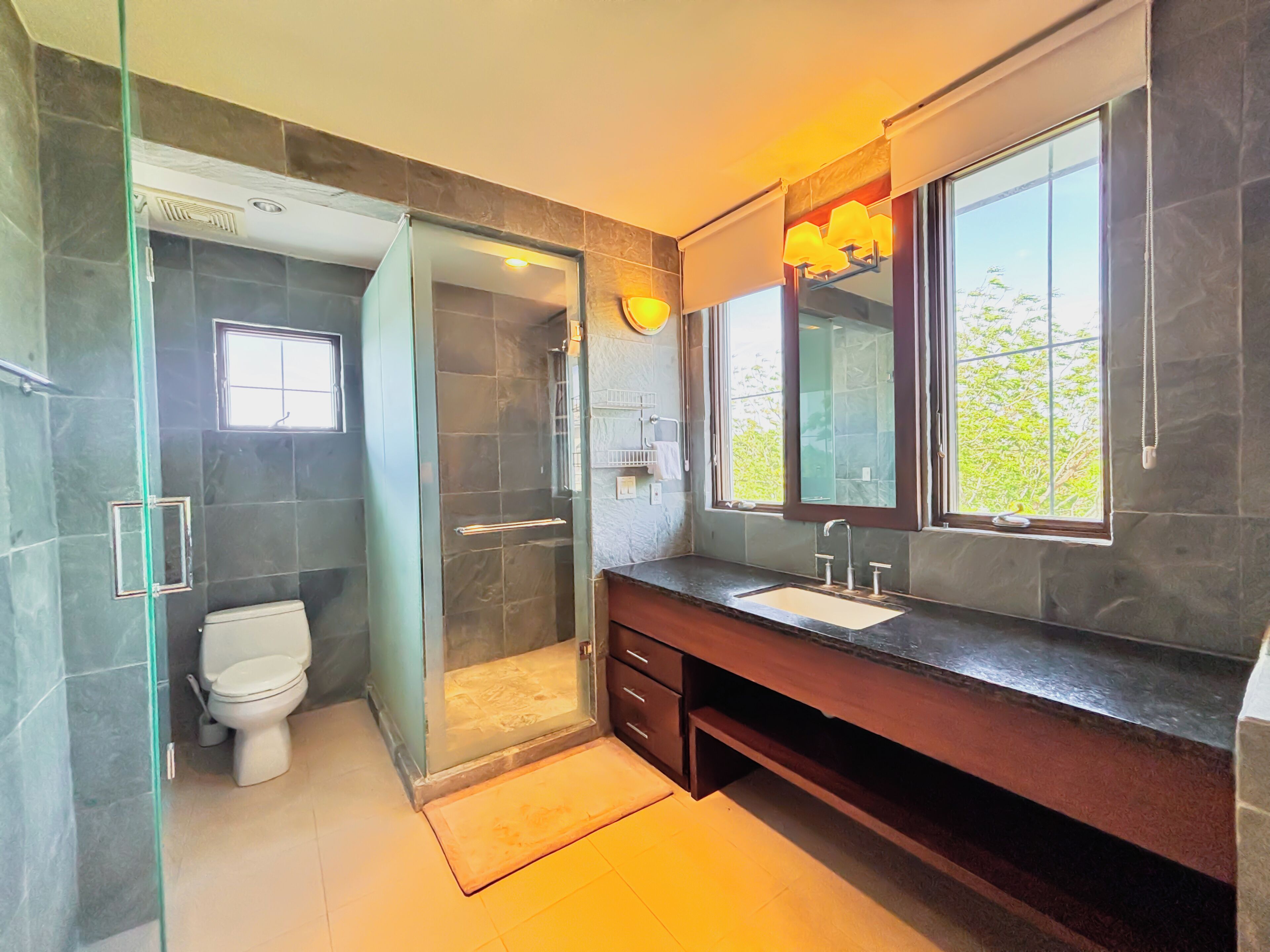 Ein modernes Badezimmer mit einer Duschkabine, einer Toilette, einem Waschbecken mit Spiegel und einem Fenster für natürliches Licht.