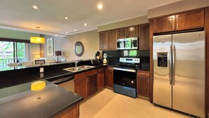 A modern kitchen with stainless steel appliances, wooden cabinets, and a large island. - Stylish 1BR Loft - Plaza Buenaventura Resort (Rio Hato, Coclé)