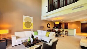 A spacious living area with a white sofa, a dining table, and a kitchen in the background. - Stylish 1BR Loft - Plaza Buenaventura Resort (Rio Hato, Coclé)