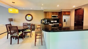 A modern kitchen with a central island, wooden cabinets, a microwave, and a refrigerator. - Stylish 1BR Loft - Plaza Buenaventura Resort (Rio Hato, Coclé)