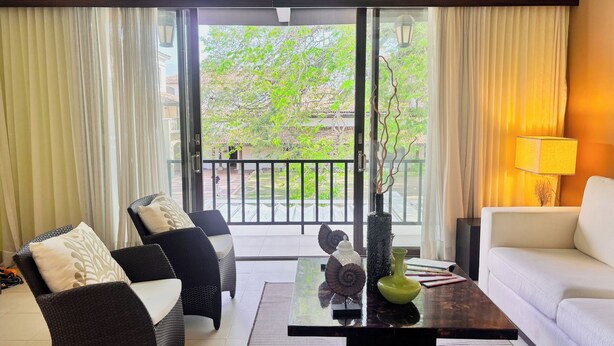 A living room with a sofa, chairs, a coffee table, and a view of greenery outside. - Stylish 1BR Loft - Plaza Buenaventura Resort (Rio Hato, Coclé)