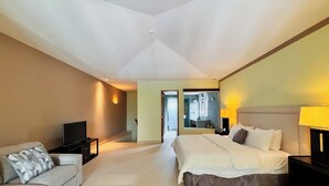 A spacious bedroom with a large bed, a sofa, a TV, and a mirror. - Stylish 1BR Loft - Plaza Buenaventura Resort (Rio Hato, Coclé)