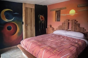 A bedroom with a bed, a wooden headboard, a mural with celestial designs, and a door. - Viewpoint of the waters (Sesquilé)