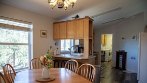 Une cuisine moderne avec des meubles en bois, une table à manger avec des chaises et une vue sur l’extérieur grâce à une grande fenêtre.