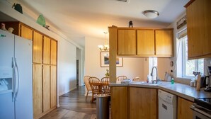 Une cuisine dotée de meubles en bois, d’un réfrigérateur, d’un lave-vaisselle et d’un coin repas avec des chaises.