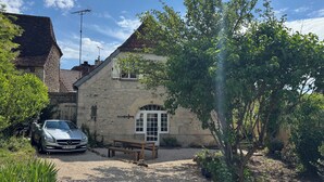 A stone building with a sloped roof, a wooden bench, and a parked car.