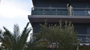 Un edificio de varios pisos con balcones, palmeras y cielo despejado.