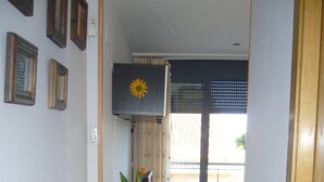 Un pasillo con una planta en maceta, un ventilador de techo y una puerta que da a un balcón.
