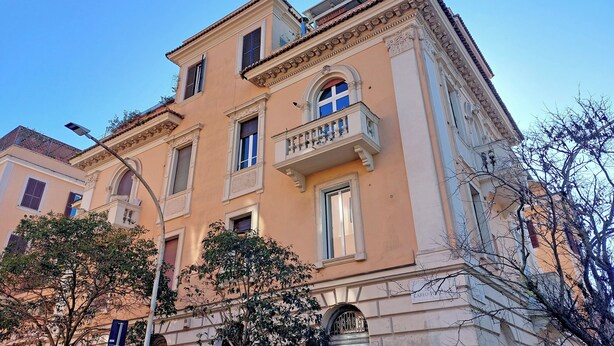 Un edificio de varios pisos con arquitectura clásica, con ventanas arqueadas y balcones decorativos.