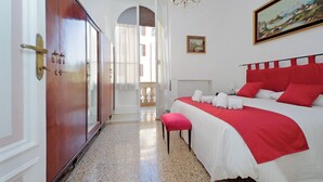Habitación de hotel con una cama grande, una pared de acento roja, una araña y un cuadro.
