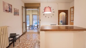 A kitchen with a clock, a radiator, and a table with a laptop. - Spacious Family Apartment in Pigneto  (Rome)