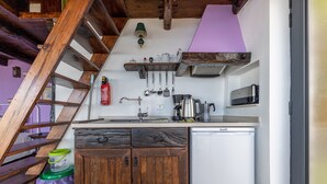 Eine kleine Küche mit Holzausstattung, einem weißen Kühlschrank und einer Holztreppe.