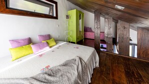 Ein Schlafzimmer mit einem Bett, Kissen, einem grünen Kleiderschrank und einer Holzbalkendecke.