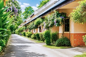 A row of buildings with a covered walkway, greenery, and hanging plants. - Chalet De Palm Resort Hatyai (Hat Yai)