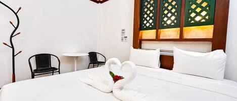 A hotel room with a bed, two chairs, a small table, and a decorative wall panel.