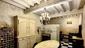 Um quarto com piso xadrez, uma mesa redonda e um candelabro.