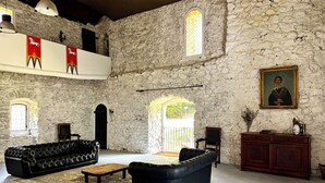 Um quarto espaçoso com paredes de pedra, um sofá de couro preto, uma mesa de centro de madeira e um quadro na parede.