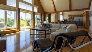 A spacious living room with a large sofa, a dining table, and a kitchen area with wooden cabinets and a refrigerator. - Amazing waterfront luxury home in millionaire area only minutes from town (Tobermory)