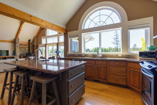 Una cocina amplia con una isla grande, armarios de madera y una pared decorativa de piedra.