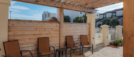 Een terras buiten met houten stoelen en een pergola.