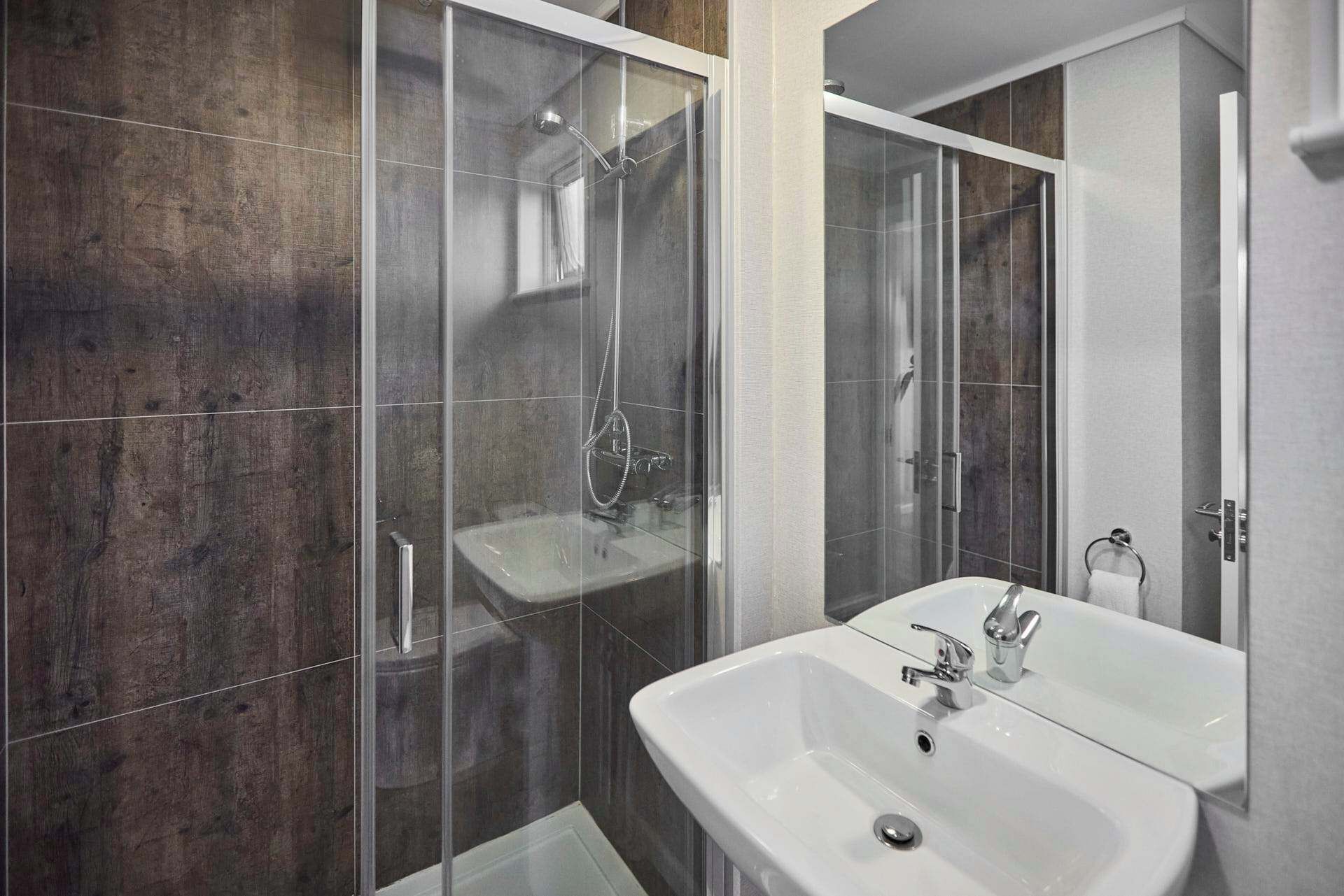 A modern bathroom with a glass-enclosed shower, a white sink, and a mirror.