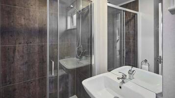 A modern bathroom with a glass-enclosed shower, a white sink, and a mirror.