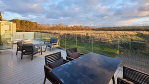 Une terrasse dotée de mobilier d’extérieur, d’une véranda et offrant une vue sur un champ.