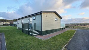 Une maison mobile de plain-pied avec un porche à l’avant et une allée goudronnée.