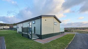 A single-story mobile home with a front porch and a paved driveway.