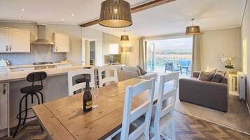 A modern kitchen with white cabinets, a wooden dining table, and a view of the outdoors.