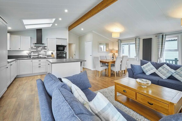 A modern kitchen with white cabinets, a central island, and a dining area with a table and chairs.